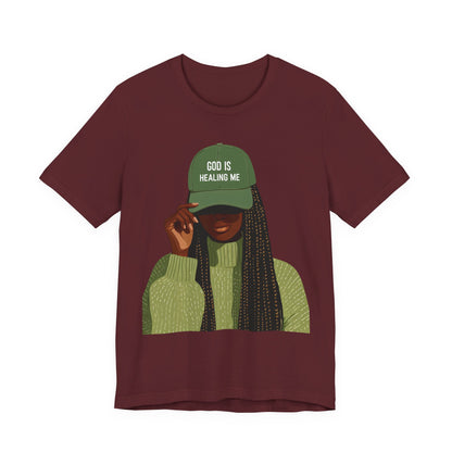 God Is Healing Me Tee — Inspirational Faith T‑Shirt with Green Cap Graphic