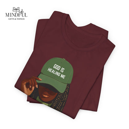 God Is Healing Me Tee — Inspirational Faith T‑Shirt with Green Cap Graphic