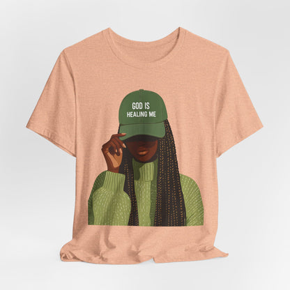 God Is Healing Me Tee — Inspirational Faith T‑Shirt with Green Cap Graphic
