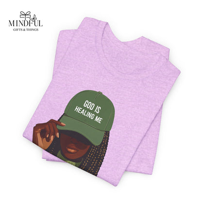God Is Healing Me Tee — Inspirational Faith T‑Shirt with Green Cap Graphic
