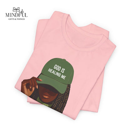 God Is Healing Me Tee — Inspirational Faith T‑Shirt with Green Cap Graphic
