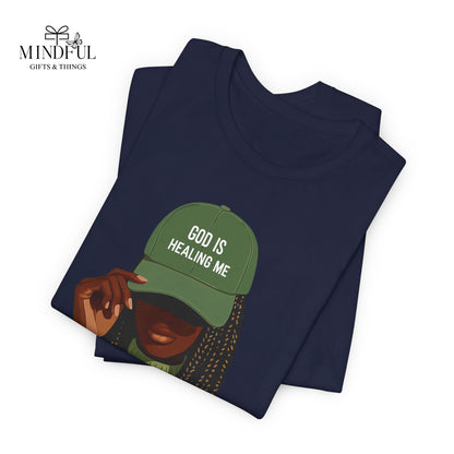 God Is Healing Me Tee — Inspirational Faith T‑Shirt with Green Cap Graphic