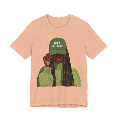 God Is Healing Me Tee — Inspirational Faith T‑Shirt with Green Cap Graphic