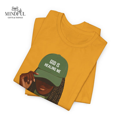 God Is Healing Me Tee — Inspirational Faith T‑Shirt with Green Cap Graphic