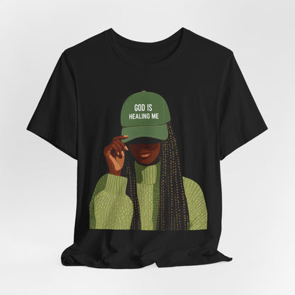 God Is Healing Me Tee — Inspirational Faith T‑Shirt with Green Cap Graphic