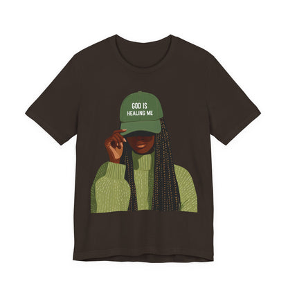 God Is Healing Me Tee — Inspirational Faith T‑Shirt with Green Cap Graphic