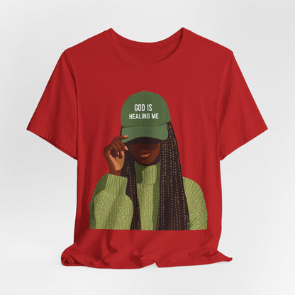 God Is Healing Me Tee — Inspirational Faith T‑Shirt with Green Cap Graphic