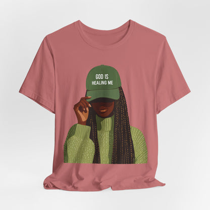 God Is Healing Me Tee — Inspirational Faith T‑Shirt with Green Cap Graphic