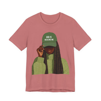 God Is Healing Me Tee — Inspirational Faith T‑Shirt with Green Cap Graphic