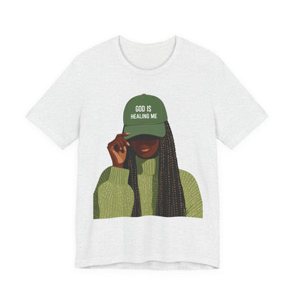 God Is Healing Me Tee — Inspirational Faith T‑Shirt with Green Cap Graphic