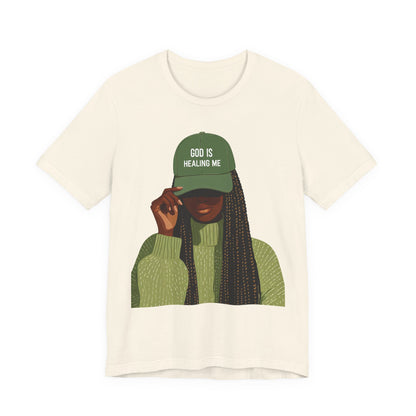 God Is Healing Me Tee — Inspirational Faith T‑Shirt with Green Cap Graphic