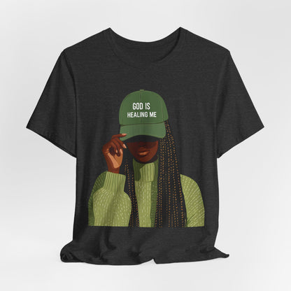 God Is Healing Me Tee — Inspirational Faith T‑Shirt with Green Cap Graphic