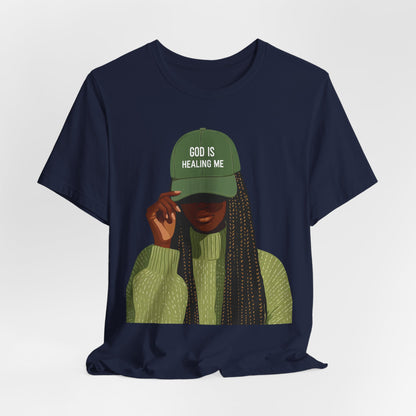 God Is Healing Me Tee — Inspirational Faith T‑Shirt with Green Cap Graphic
