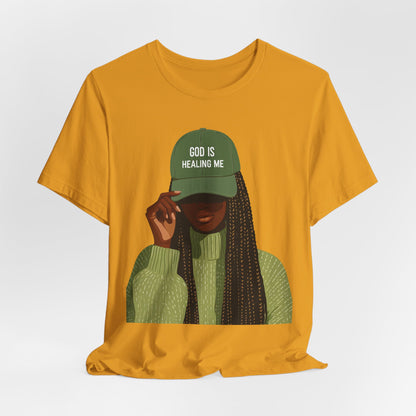 God Is Healing Me Tee — Inspirational Faith T‑Shirt with Green Cap Graphic